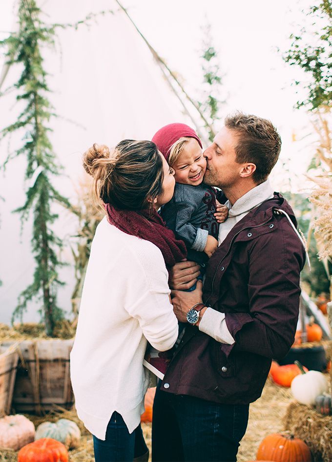 a man, woman and child standing in front of pumpkins