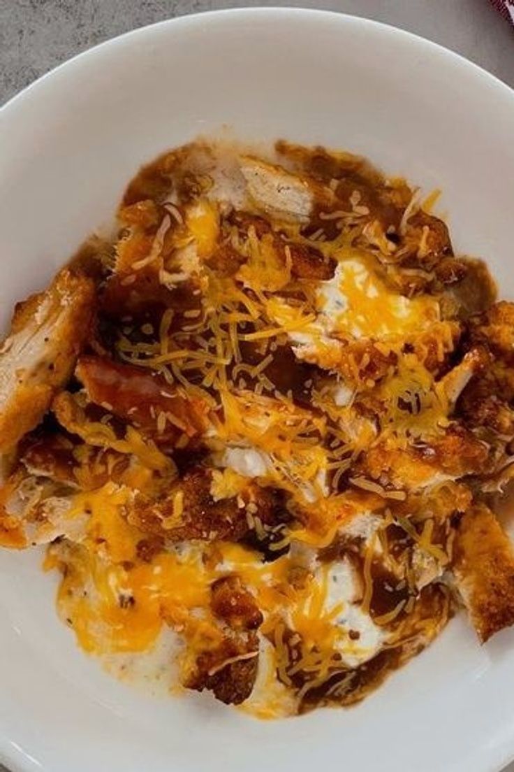 a white plate topped with meat and cheese covered in sauce on top of a table