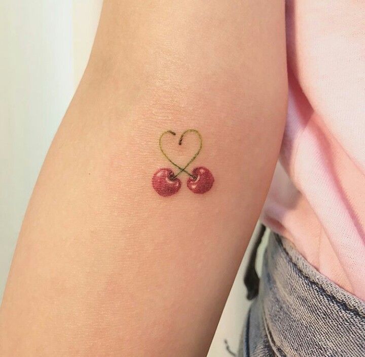 two cherries in the shape of a heart tattoo on the left forearm and right arm