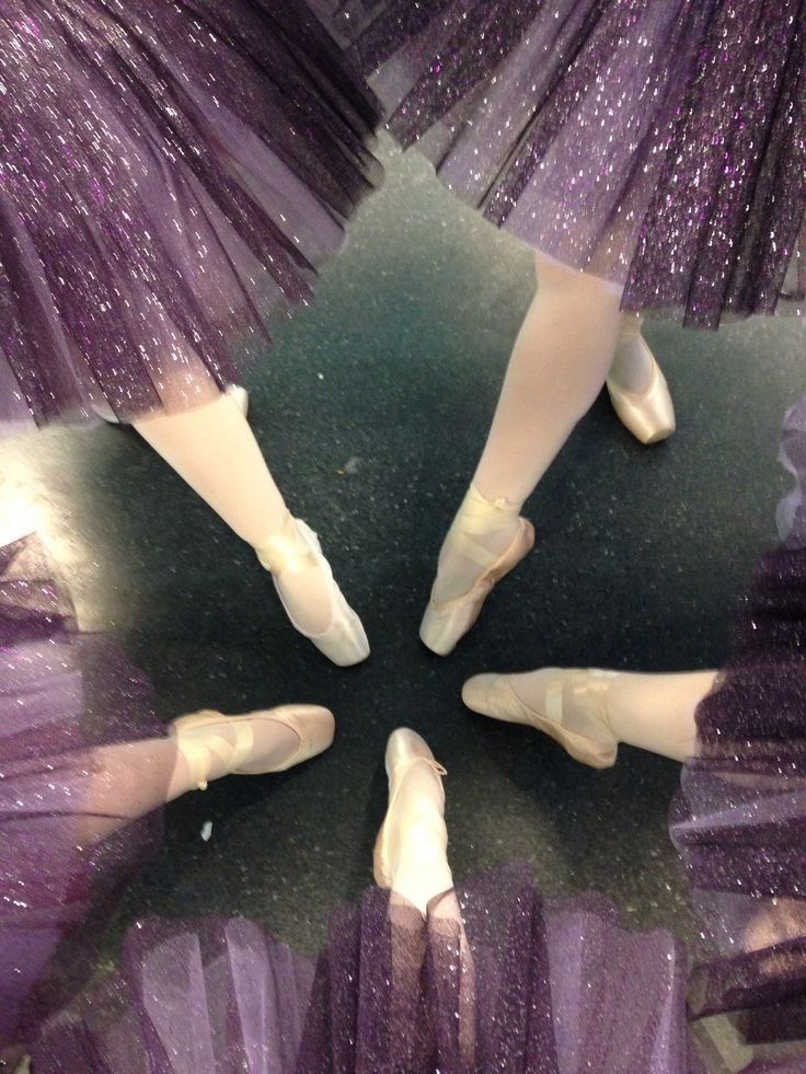 four ballerinas are standing in a circle on the floor with their feet up