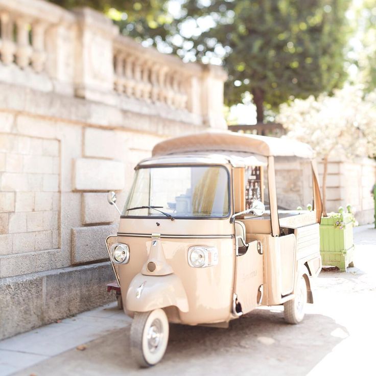 an old car is parked on the side of the road next to a stone wall