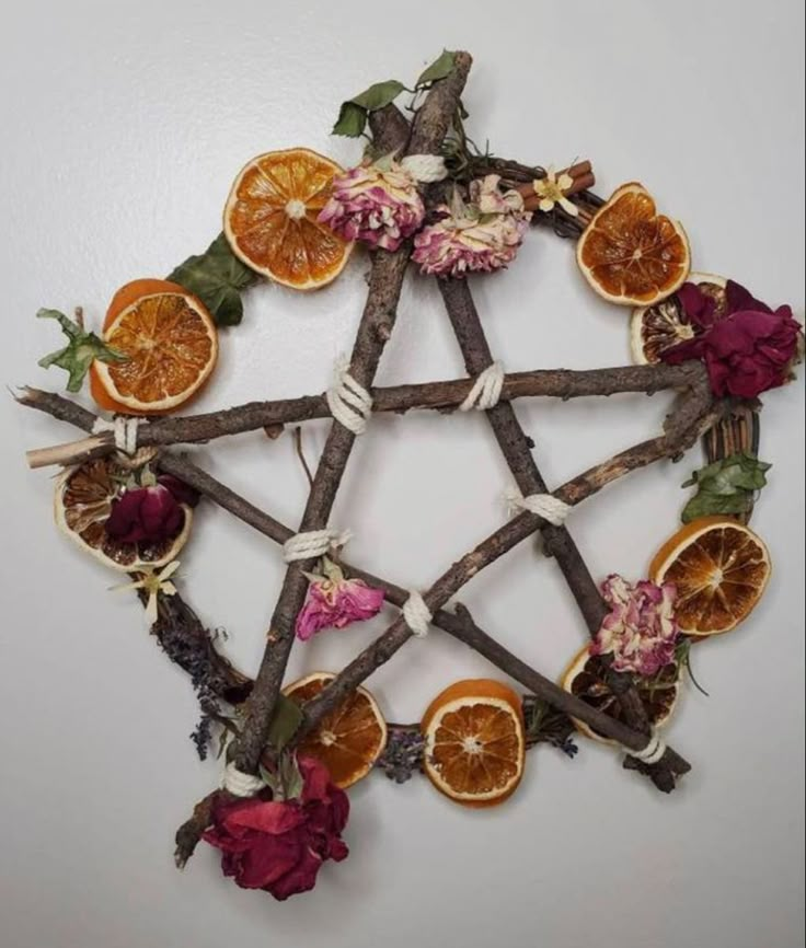 an arrangement of dried fruit arranged in a pentagram with leaves and flowers on it