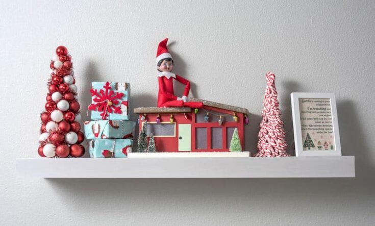 an elf is sitting on top of a shelf next to christmas decorations and gifts,