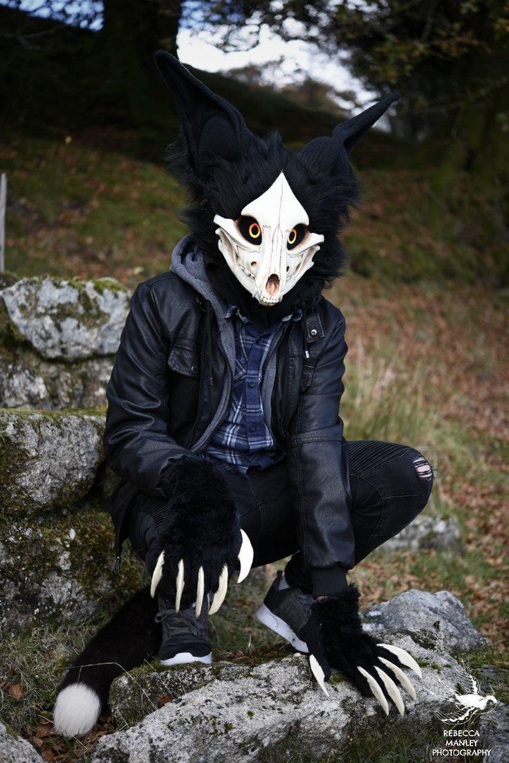 a person wearing an animal mask sitting on some rocks