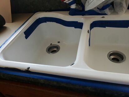 two white sinks sitting on top of a kitchen counter under construction tape and some scissors