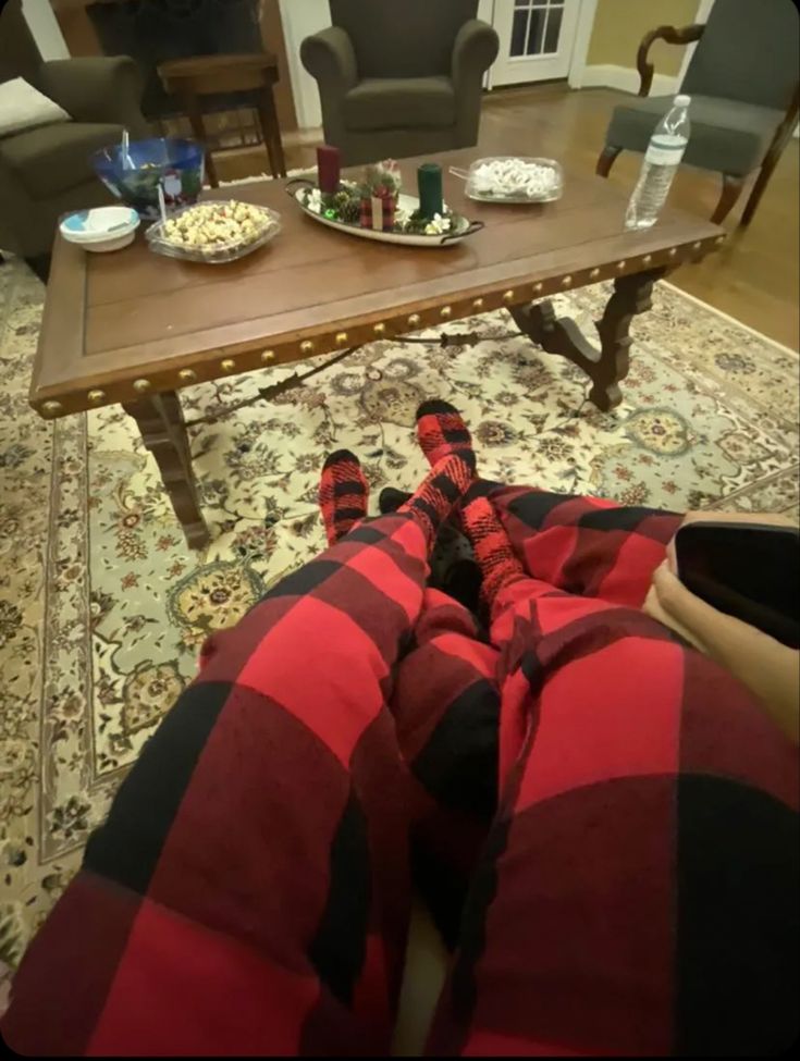 two people are sitting on the floor with their feet up in front of a coffee table