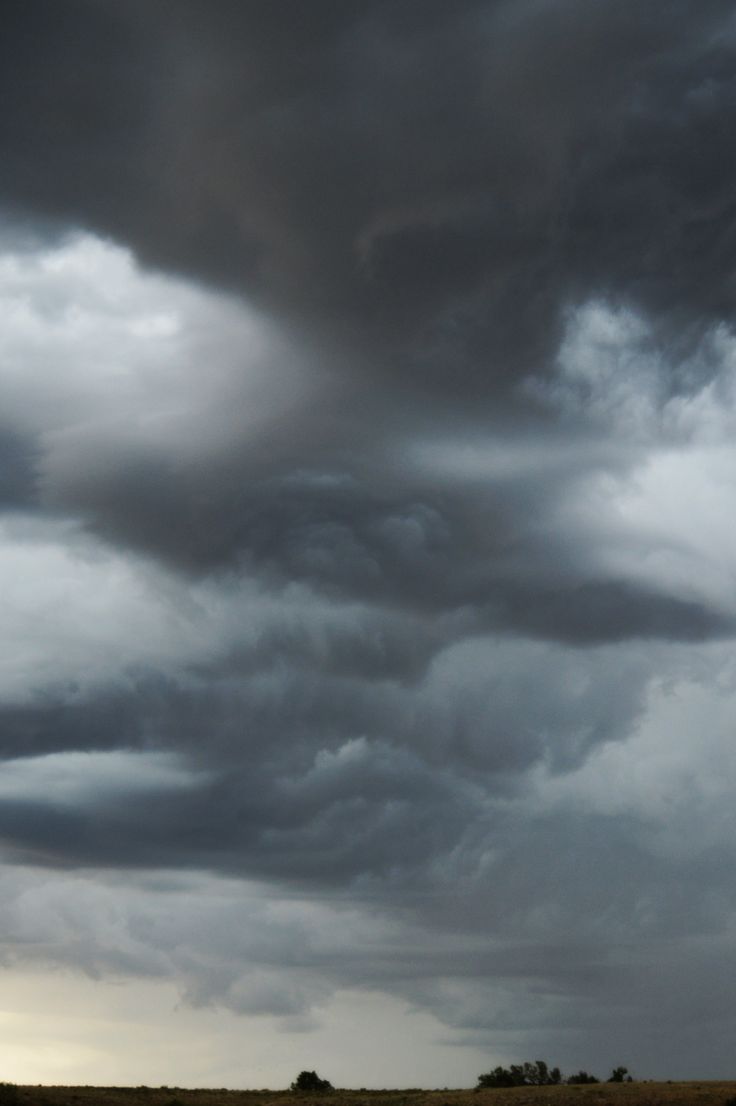 the sky is filled with dark clouds over an open field