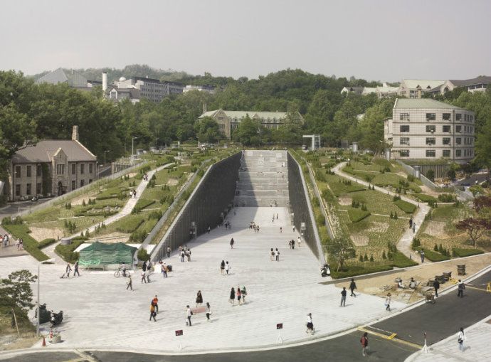 an aerial view of people walking and sitting on the steps in front of a park