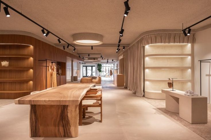 the interior of a store with wooden tables and shelves on either side of the room