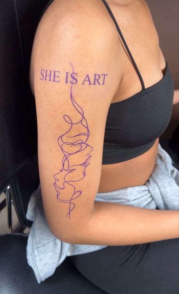 a woman with a tattoo on her arm that reads she is art, and the words are