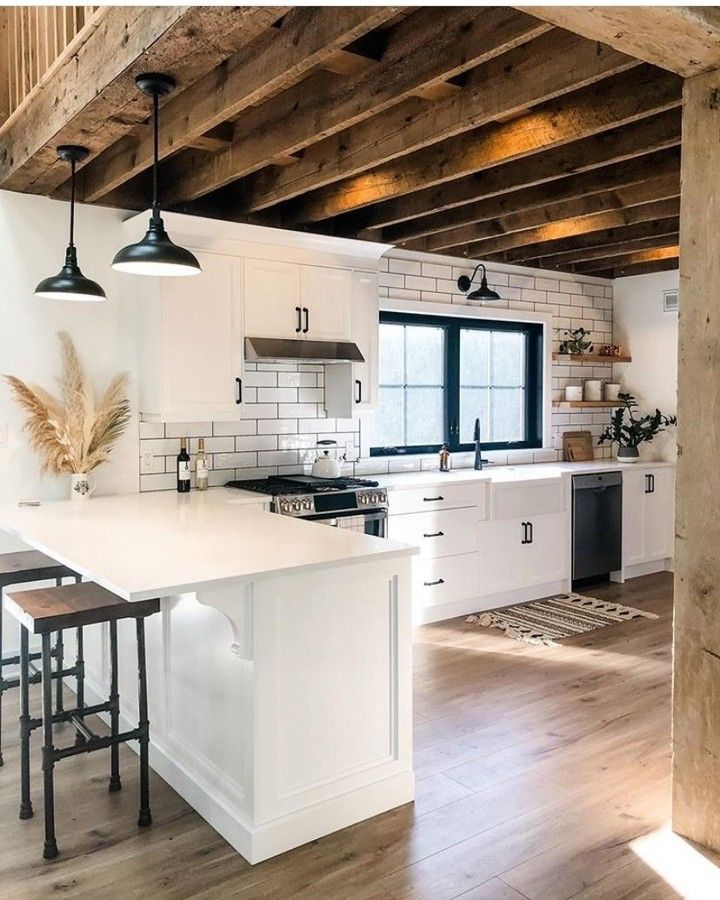 an open concept kitchen with white cabinets and wood flooring is featured in this image