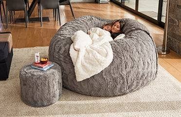 a woman laying on top of a bean bag chair in a living room next to a coffee table