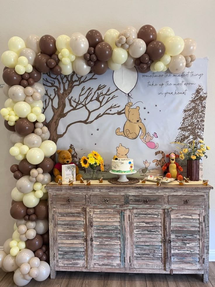 a winnie the pooh birthday party with balloons, cake and dessert table set up