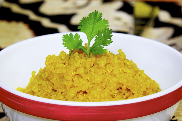 a white bowl filled with yellow rice and parsley