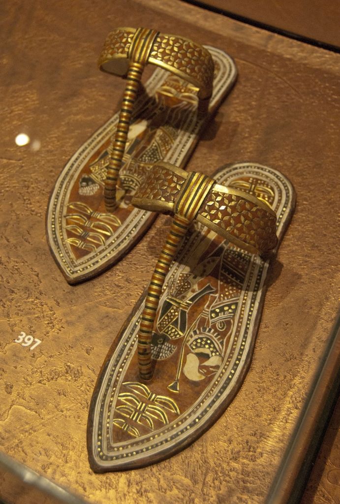 a pair of sandals sitting on top of a wooden table next to a glass case