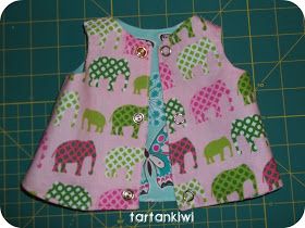 a close up of a pink and green dress with elephants on it, sitting on a cutting board