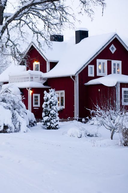 a red house covered in snow next to trees