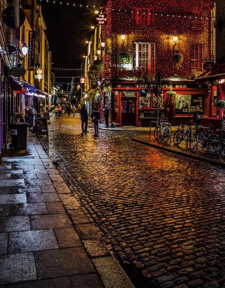 a cobblestone street at night with people walking on it