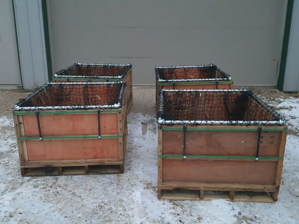 two wooden crates sitting next to each other on snow covered ground in front of a garage door