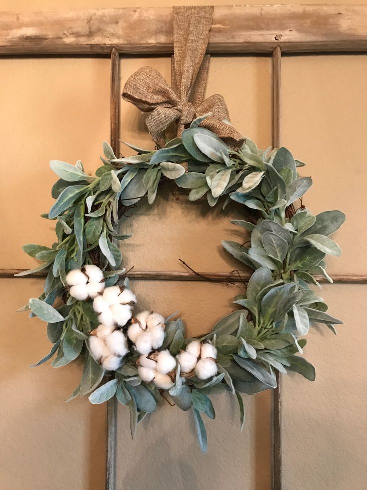 a wreath hanging on the front door with cotton balls and greenery around it's edges