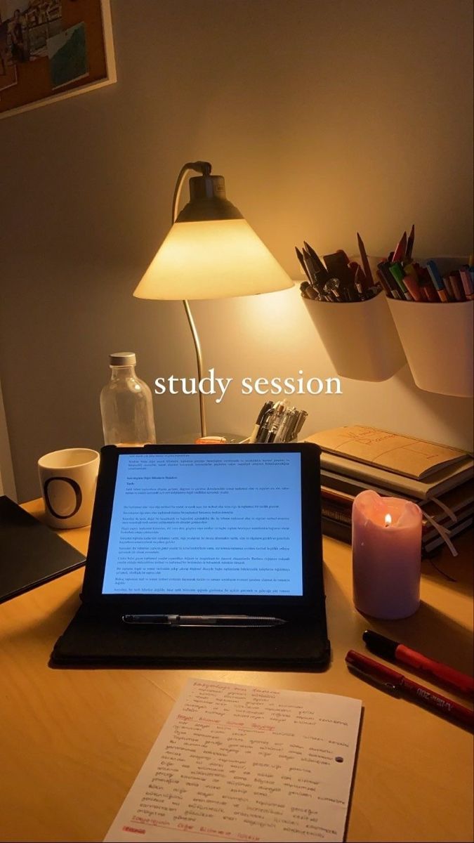 an open laptop computer sitting on top of a wooden desk next to a lit candle