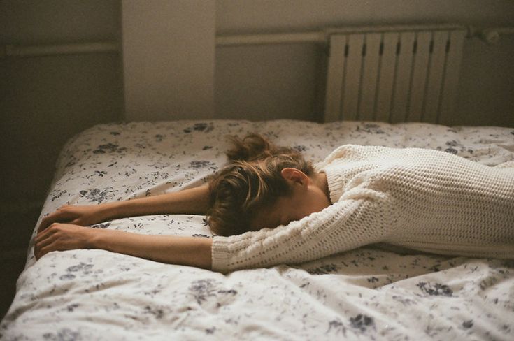 a woman laying on top of a bed under a blanket