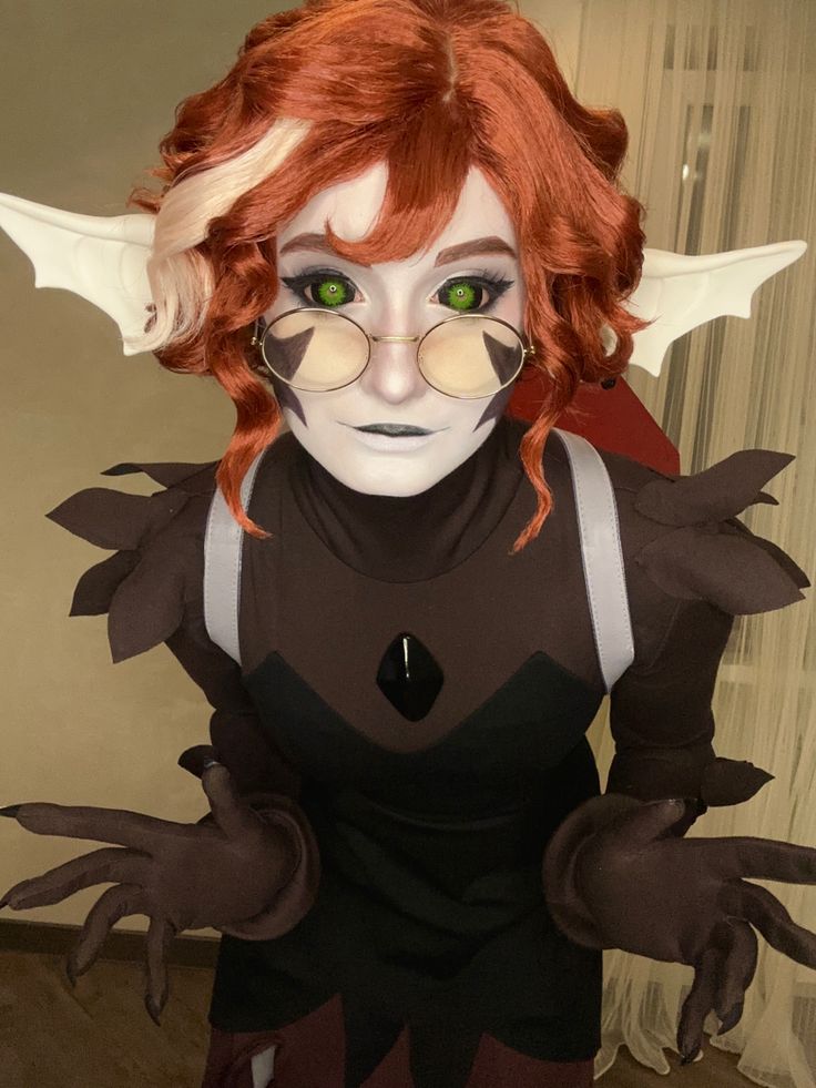 a woman with red hair and green eyes is dressed up as an evil looking creature