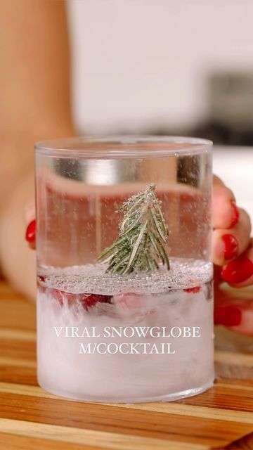 a woman is holding a glass with a small tree in it and the words virtual snowglobe moscow