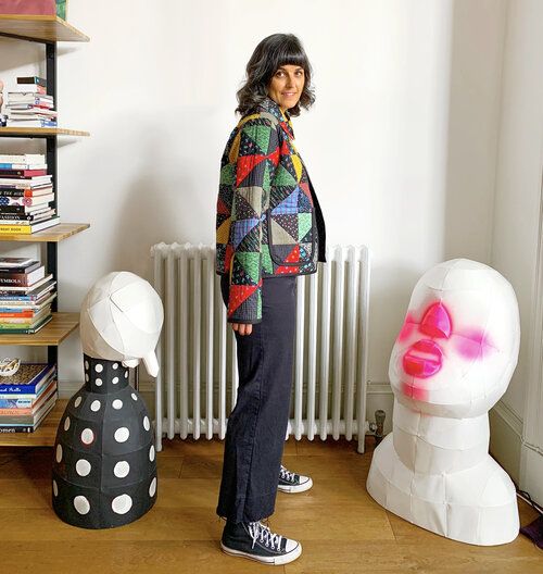 a woman standing in front of some fake heads and bookshelves on the floor