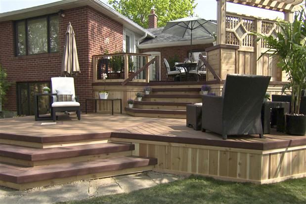 a deck with chairs and umbrellas in front of a house