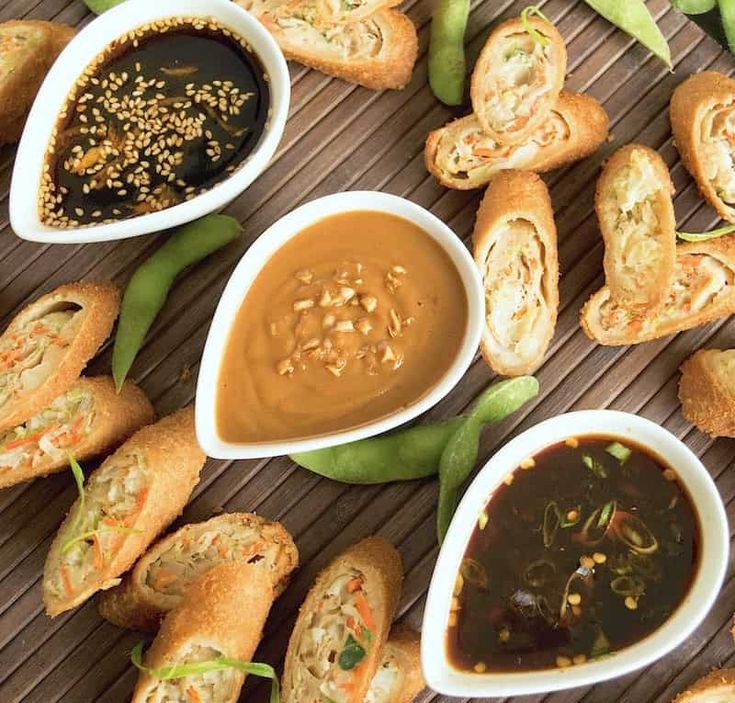 several small bowls filled with food on top of a wooden table next to green beans