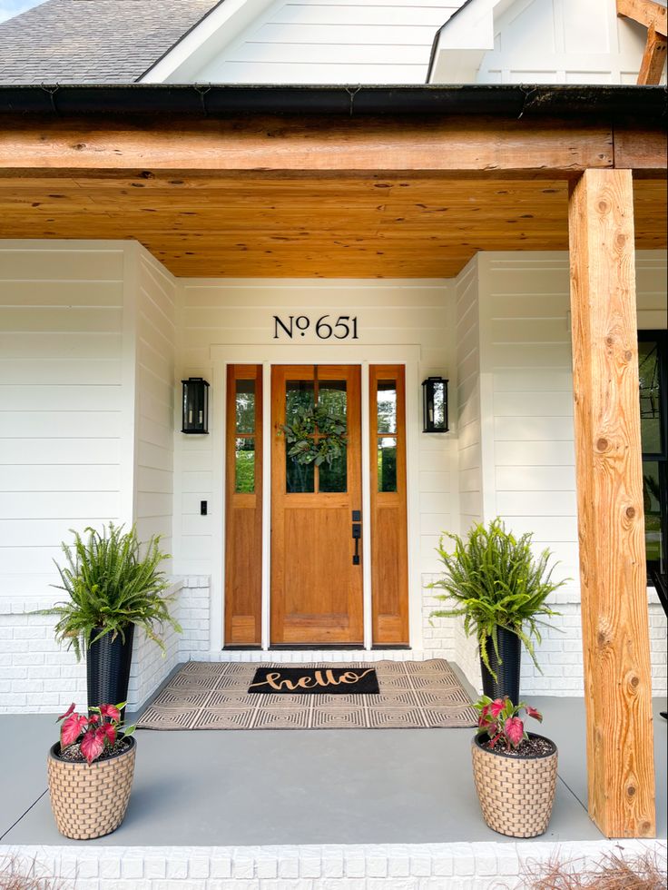 two potted plants sitting on the front porch of a house with no 051 written on it