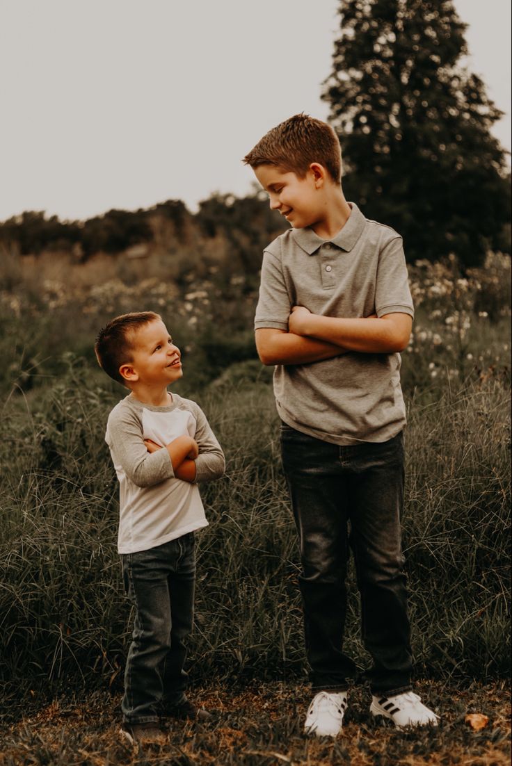 two young boys standing next to each other in a field