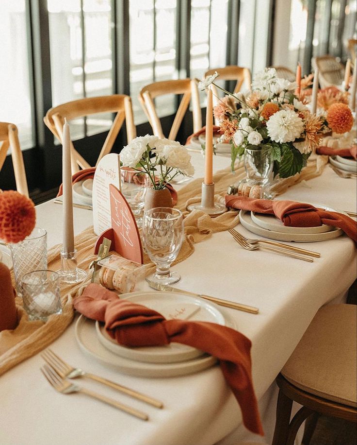 the table is set with place settings and flowers in vases, candles, and napkins