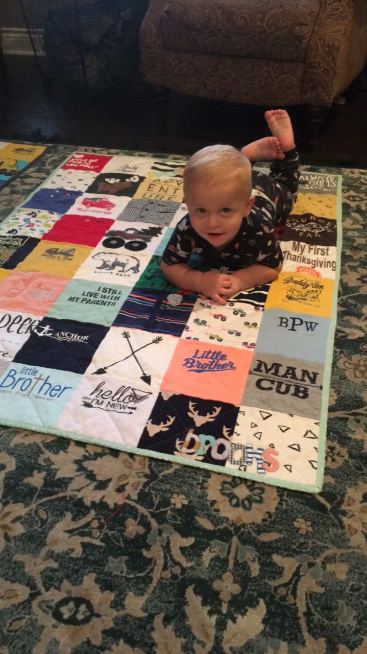 a baby sitting on top of a colorful patchwork blanket in front of a couch