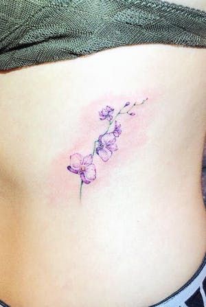 a woman's stomach with a small flower tattoo on the side of her belly