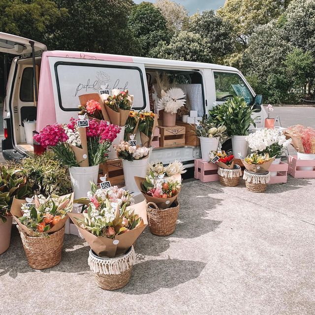 a van parked next to a bunch of flowers in baskets on the side of the road