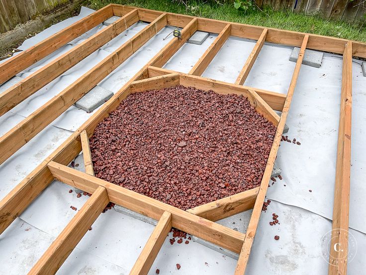 a wooden frame filled with red gravel sitting on top of cement