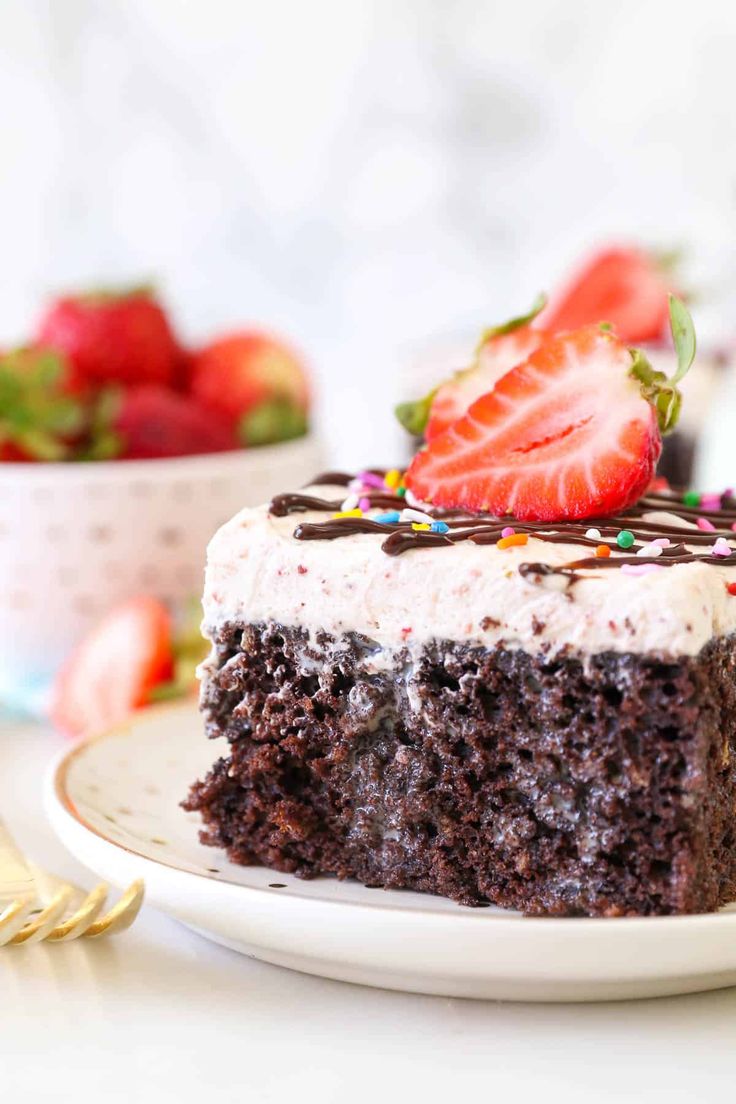 a slice of chocolate cake on a plate with strawberries and sprinkles