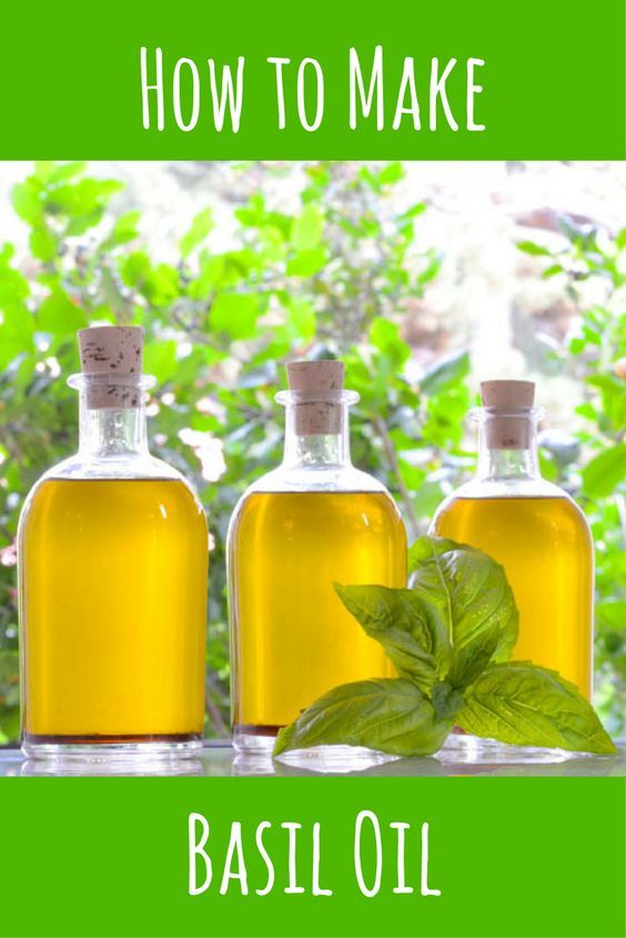 three bottles filled with basil oil sitting on top of a table next to a window