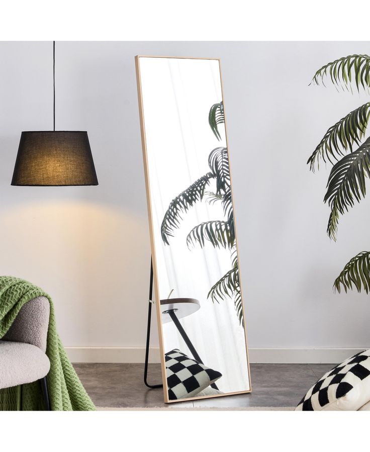 a large mirror sitting on top of a floor next to a chair and lamp in a room