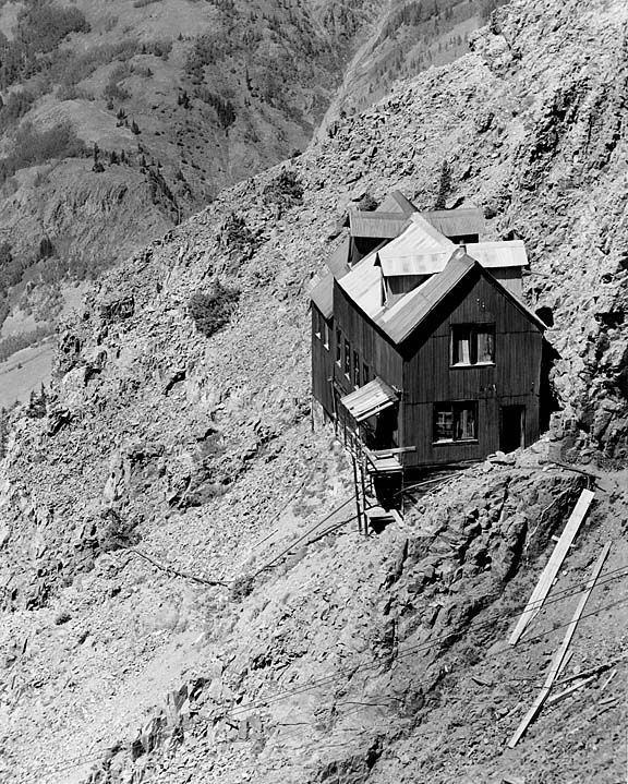 a black and white photo of a house on the side of a mountain