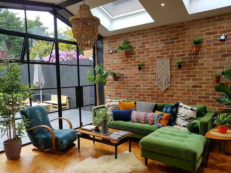 a living room filled with lots of furniture next to a brick wall covered in potted plants