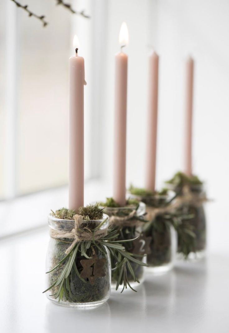 four candles with moss in them are sitting on a table