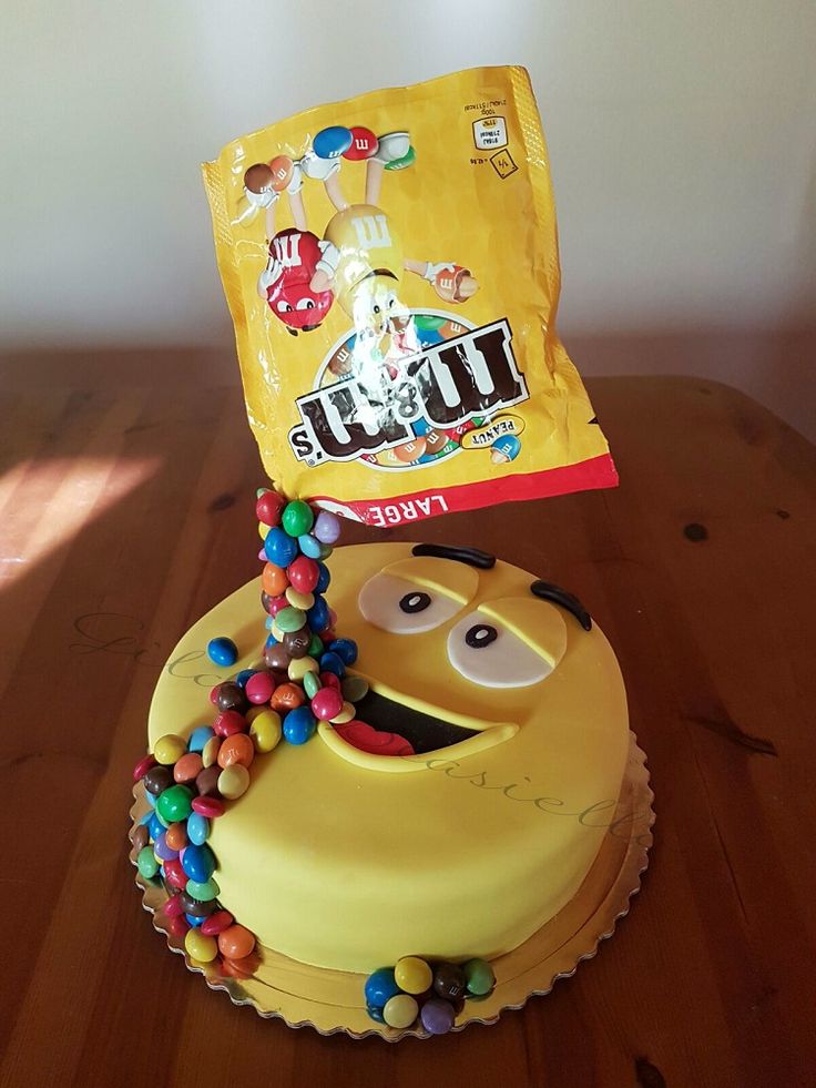 a yellow cake with candy on top and a bag of m & m's next to it