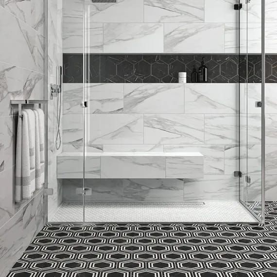 a bathroom with black and white tile flooring and walls, along with a walk in shower