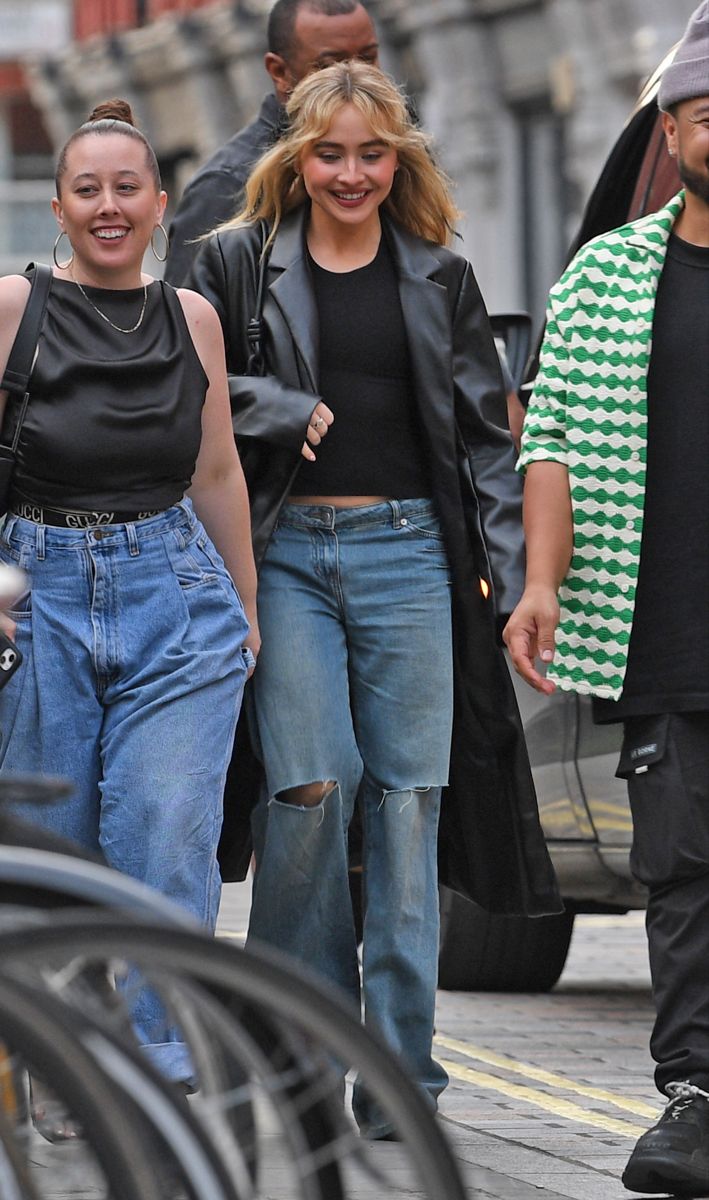 two women walking down the street with one woman wearing high waist jeans and black top