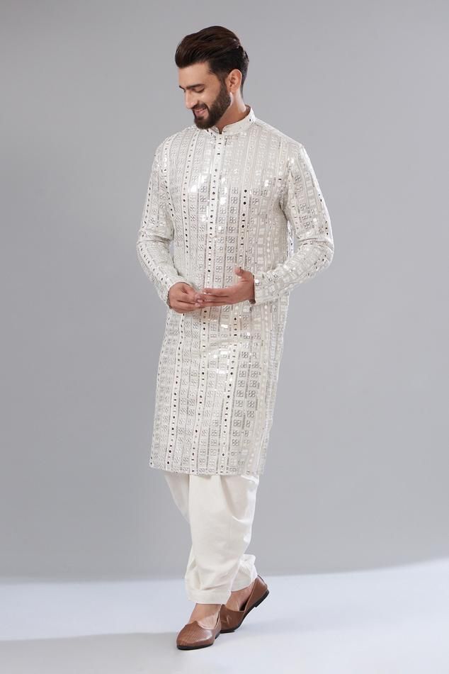 White kurta with silver mirror and sequin embroidery, a mandarin collar and long sleeves.
Components: 1
Pattern: Embroidered
Type Of Work: Sequin, Mirror
Neckline: Mandarin collar
Sleeve Type: Sleeveless
Fabric: Georgette
Color: White
Other Details: 
Attached cotton lining
Note: Pant worn by the model is not for sale.
Occasion: Mehendi and Puja, Sangeet - Aza Fashions Silver Bollywood Kurta With Zari Work, Festive Silver Kurta With Zari Work, Festive Silver Kurta For Festivals, Traditional Silver Kurta With Zari Work, Silver Kurta With Zari Work For Diwali, Silver Traditional Kurta For Festive Occasions, Luxury White Kurta With Mirror Work, Silver Traditional Wear With Mirror Work For Eid, Traditional Silver Kurta With Resham Embroidery