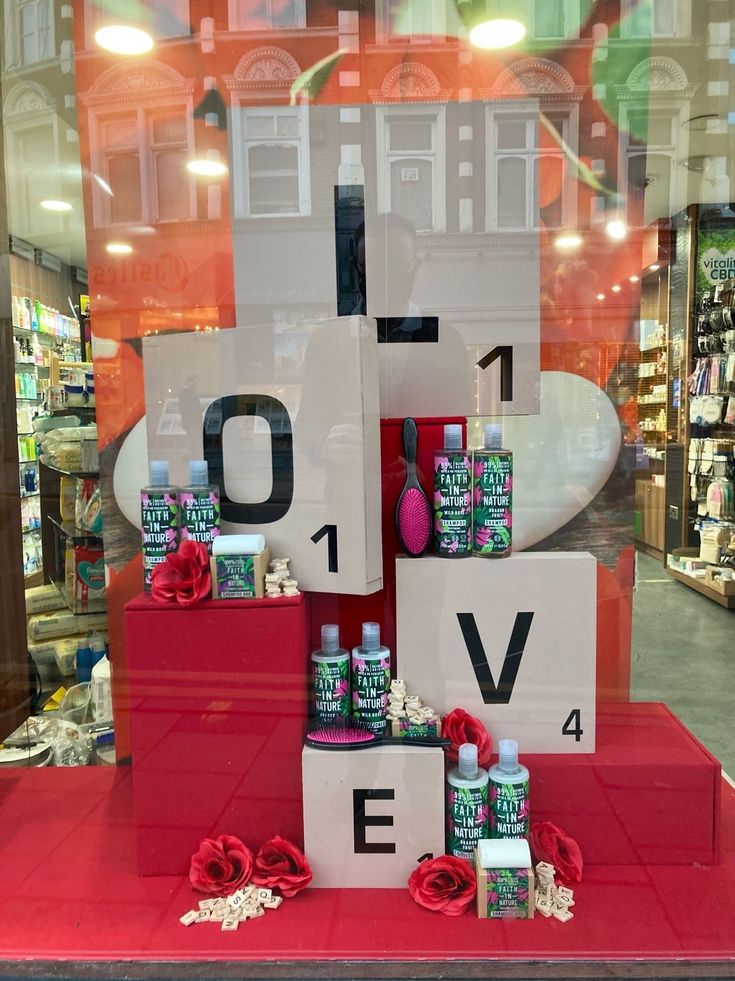 a display window with bottles and flowers on it in front of a storefront that has the words love spelled out