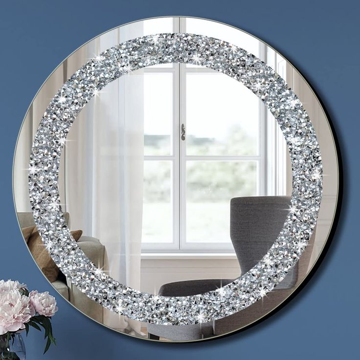 a round mirror sitting on top of a wall next to a vase filled with flowers